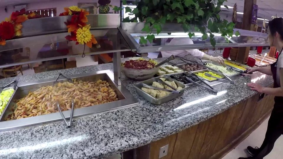 Seafood buffet line with hot trays and serving spoons.
